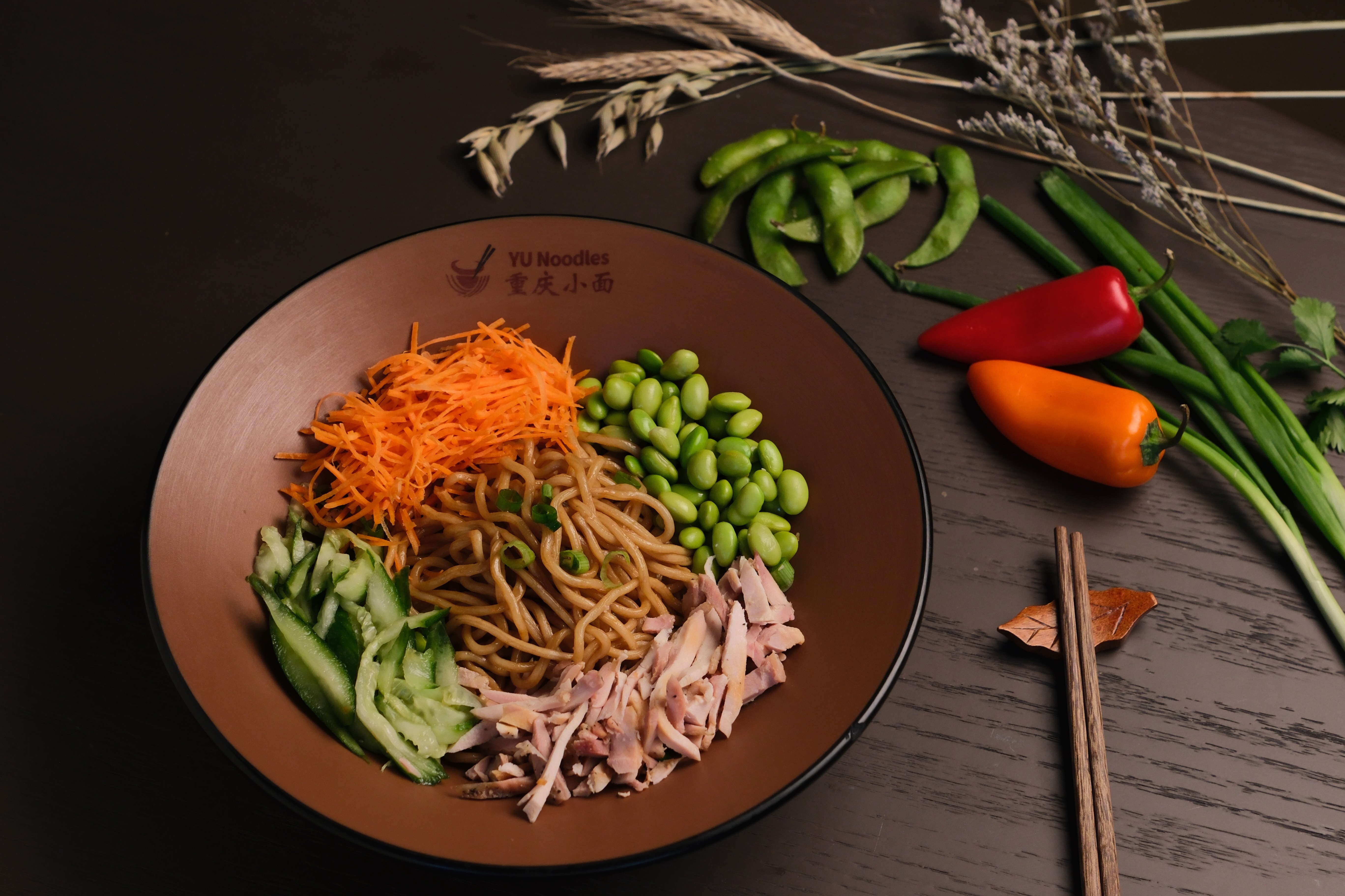A chilled dressed noodle bowl with vegetables and shredded chicken